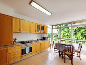 Een keuken met houten kastjes, een gasfornuis en een eethoek met een tafel en stoelen.
