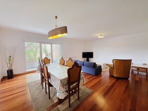 Een eethoek met een tafel en stoelen, een bank, een televisie en een raam met uitzicht.