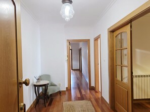 Ein Flur mit Holzboden, einem Stuhl, einem Tisch und einer Tür mit Fensterteil.