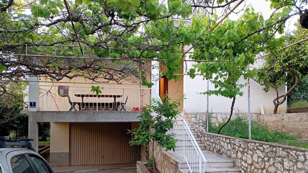 Un quartier résidentiel avec un escalier en pierre menant à une maison, une voiture garée et un arbre aux feuilles vertes.