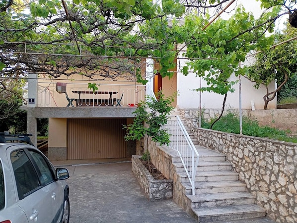 A residential area with a stone staircase leading to a house, a parked car, and a tree with green leaves. - Cozy Apartment in Trogir (Trogir)