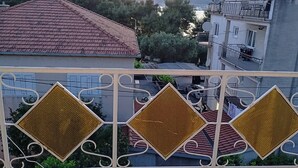 Un immeuble résidentiel avec un toit recouvert de tuiles rouges, un balcon orné de balustrades en métal décoratives et des antennes paraboliques sur le toit.