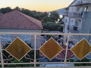 A residential building with a red-tiled roof, a balcony with decorative metal railings, and satellite dishes on the roof. - Cozy Apartment in Trogir (Trogir)