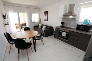 Eine moderne Küche mit Essbereich, einer Couch und einem Fernseher.