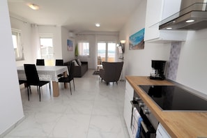 A modern kitchen with a dining area, a view to the outside, and a flat-screen TV mounted on the wall. - Nice 2 Bed Apartment (Okrug)