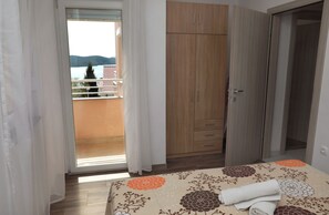 A bedroom with a bed, a wardrobe, and a balcony with a view. - Nice 2 Bed Apartment (Okrug)