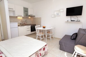 A compact living space with a kitchenette, a dining area, a sofa, and a TV mounted on the wall. - Apartment Stella Maree 3 (Okrug)