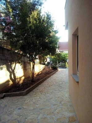 A stone-paved courtyard with a tree and a wall. - Apartment Stella Maree 3 (Okrug)