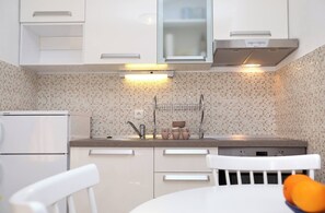 A modern kitchen with white cabinets, a stainless steel range hood, and a tiled backsplash. - Apartment Stella Maree 3 (Okrug)
