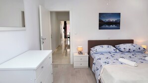 A bedroom with a bed, bedside tables, a nightstand, a mirror, a ceiling fan, and a painting on the wall. - Charming 2-bedroom Apartment With Stunning Views in Okrug Gornji (Okrug)