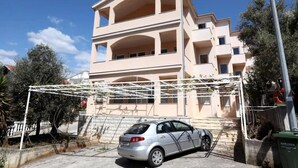 A multi-story building with balconies, a car parked in front, and a metal structure to the left. - Charming 2-bedroom Apartment With Stunning Views in Okrug Gornji (Okrug)