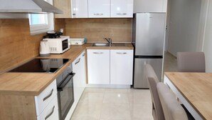 A modern kitchen with white cabinets, a stainless steel refrigerator, a microwave, and a stove. - Charming 2-bedroom Apartment With Stunning Views in Okrug Gornji (Okrug)