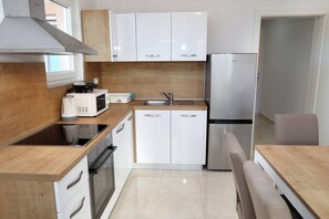 A modern kitchen with white cabinets, a stainless steel refrigerator, a microwave, and a stove. - Charming 2-bedroom Apartment With Stunning Views in Okrug Gornji (Okrug)