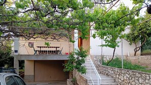 A residential area with a stone staircase leading to a house, a parked car, and a tree with green leaves. - Sunny Apartment in Trogir (Trogir)