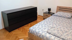 A bedroom with a bed, a wooden headboard, a nightstand, a dresser, and a lamp. - Sunny Apartment in Trogir (Trogir)