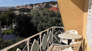 A balcony with a table and chairs, a view of a town, and a railing. - Sunny Apartment in Trogir (Trogir)