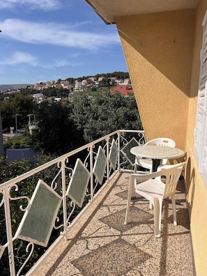 A balcony with a table and chairs, a view of a town, and a railing. - Sunny Apartment in Trogir (Trogir)