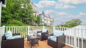 Eine Terrasse mit Korbmöbeln und einem Tisch, mit Blick auf eine Wohngegend mit Häusern und Grünflächen.