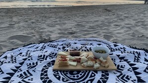 Eine Decke mit geometrischem Muster an einem Strand, im Hintergrund ein Sonnenuntergang.
