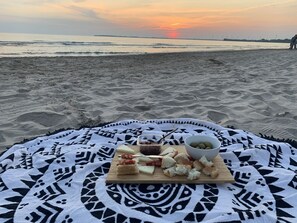 Une couverture à motifs géométriques sur une plage, avec un coucher de soleil en arrière-plan.