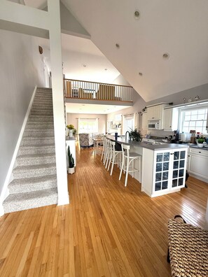 Une cuisine spacieuse dotée d’un îlot central, d’un coin repas et d’un escalier menant à l’étage supérieur.