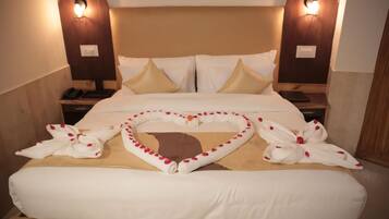 Una cama bien hecha con adornos con forma de corazón, dos lámparas de noche y un cabecero de madera.
