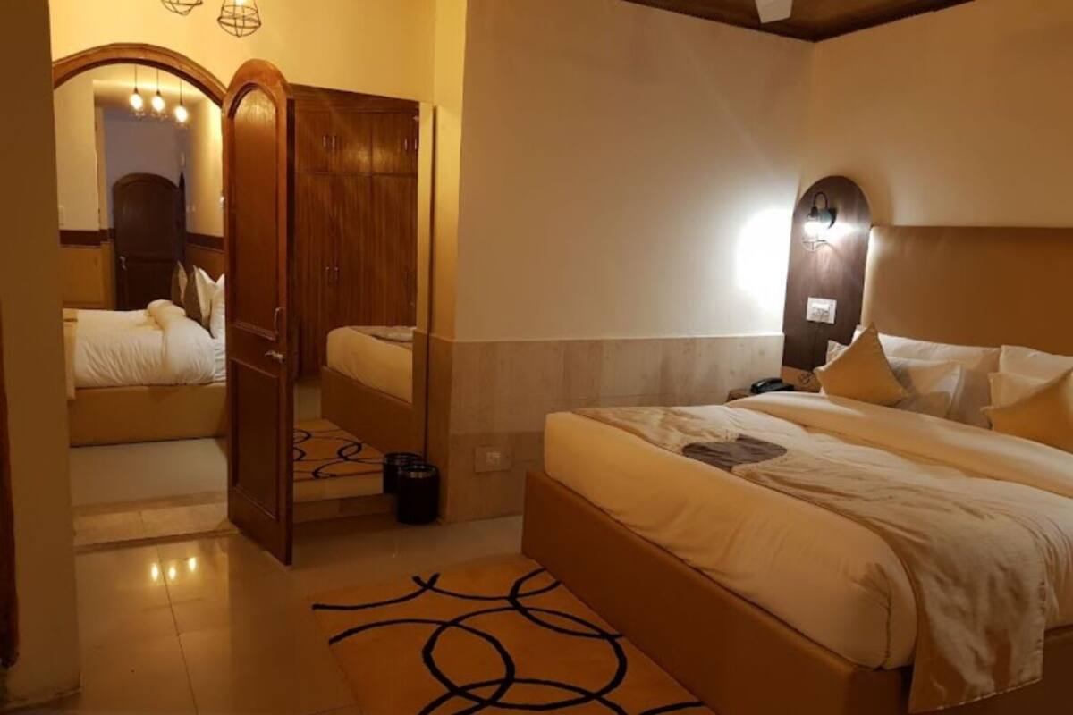 A bedroom with a large bed, a wardrobe, a mirror, and a nightstand.