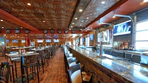 A bar with a long counter, multiple TVs, and a patterned ceiling. - Large 2-bedroom in resort near Universal Studios & Disney with water park (Orlando)