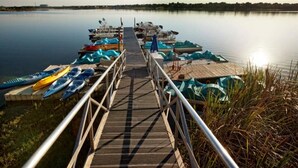 A wooden dock leading to a calm lake with kayaks and canoes docked on the right. - Large 2-bedroom in resort near Universal Studios & Disney with water park (Orlando)