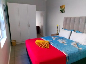 Une chambre à coucher avec un lit, une armoire, une table de chevet, une lampe et un tableau au mur.