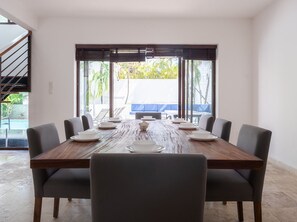 A dining area with a wooden table, eight chairs, and a view of a pool and outdoor seating. - 5min walk to beach, housekeeping, pool at terrace, oceanview jacuzzi at rooftop (Playa del Carmen)