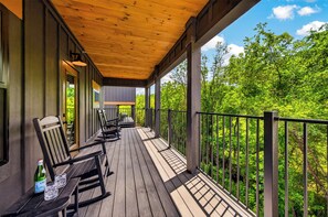 Eine Holzterrasse mit Stühlen und einem Tisch, eine Flasche und Gläser auf dem Tisch.