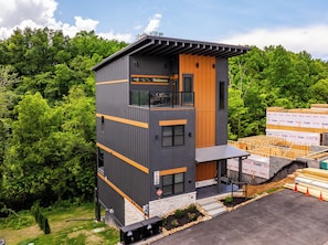 Ein modernes, zweistöckiges Gebäude mit Balkon, Steinsockel und Holztür.