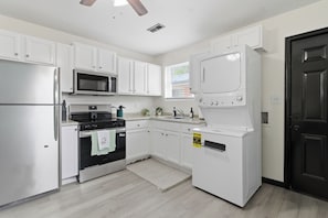 A modern kitchen with white cabinets, stainless steel appliances, a microwave, oven, and a dishwasher. - Sleeps 4, minutes from beach & Naval base (Norfolk)