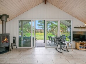 Ein modernes Wohnzimmer mit Kamin, Schiebetüren zu einer Terrasse, einem Fernseher und einem Bücherregal.