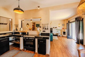 A modern kitchen with a central island, built-in oven, and a dining area with a view.