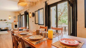 A dining area with a wooden table set for two, a glass of orange juice, and a view of the outdoors. - Charming Villa with private pool and maid (Essaouira)