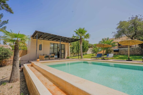 A modern house with a swimming pool, outdoor seating, and a covered patio.