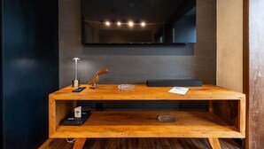 Une console en bois, surmontée d’un miroir, avec un lavabo moderne et un téléviseur à écran plat fixé au mur.