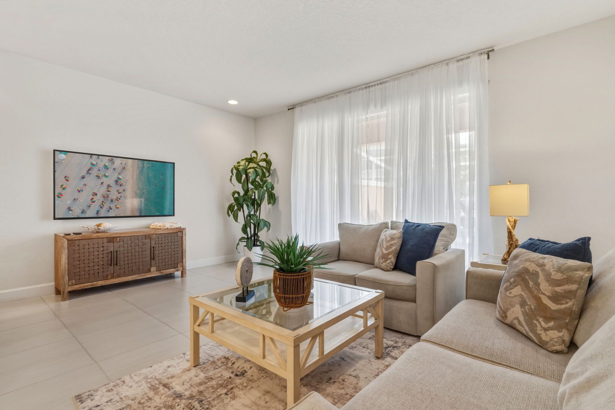A living room with a sofa, coffee table, and a TV on the wall.