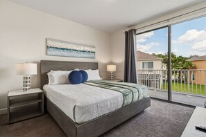 Ein Hotelzimmer mit einem großen Bett, zwei Nachttischen, einem Fenster mit Blick auf eine Wohngegend und einem Bild an der Wand.
