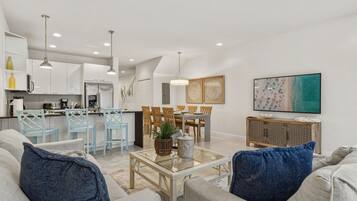 A modern living room with a sofa, coffee table, and dining area.
