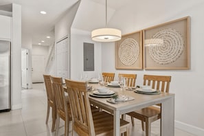 Ein Essbereich mit einem Holztisch, gedeckt für vier Personen, weißen Wänden und zwei runden Kunstwerken an der Wand.