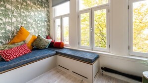 Een kamer met een inbouwkbank, grote ramen en een radiator.