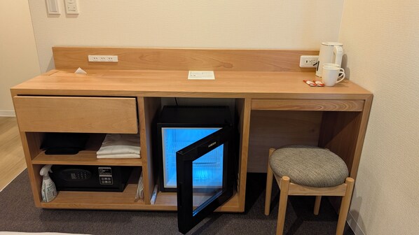 A compact wooden desk with a built-in mini-fridge, a coffee maker, and a chair. - CHECK inn Osaka Shin-Sekai (Osaka)