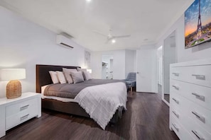 A modern bedroom with a bed, bedside table, and a dresser.