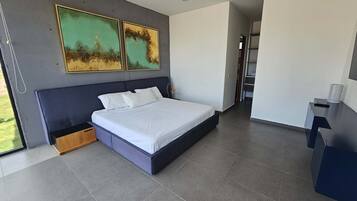 Une chambre à coucher moderne avec un grand lit, une table de chevet, un bureau et deux tableaux abstraits accrochés au mur.