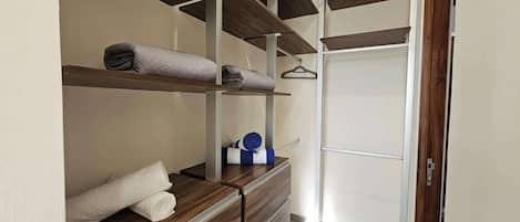 Um closet amplo com prateleiras de madeira, um cabideiro e uma porta de espelho.
