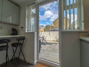 A kitchen with a window leading to a patio area. - Tide & Seek — Garden Flat by the Sea (Walmer)