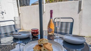 A table with a bottle of champagne, a glass, and a plate with scones. - Tide & Seek — Garden Flat by the Sea (Walmer)